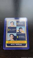 Photo of 1971/72 NHL assists leaders hockey card including Bobby Orr, Phil Esposito, and Jean Ratelle in plastic protective case