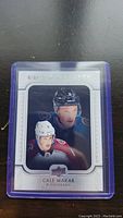 Photo of Cale Makar hockey rookie card in protective purple sleeve against dark background showing front of card with player image and details.