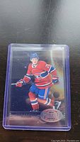 Cole Caufield rookie hockey card in Montreal Canadiens uniform from the Metal Universe series, placed on black surface inside a protective clear plastic sleeve.