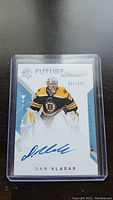 Front face of Dan Vladar Rookie autograph hockey card numbered 957/999 in protective plastic case on black surface