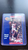 Clear photograph of 1990 Fleer Michael Jordan basketball trading card in a protective plastic sleeve, showing front side design and player action image.