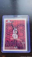 Close-up photo of Michael Jordan MVP basketball card in protective case, showing card face with red 23 background and player image.
