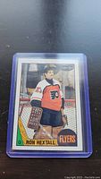 Photo of Ron Hextall rookie hockey card in protective plastic case, card shows player in Philadelphia Flyers goalie uniform with number 27.