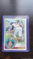 Photo of Tony Gwynn rookie baseball card from 1982 Topps set in protective plastic sleeve shown flat on black surface.