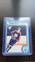 Front view of Wayne Gretzky Edmonton Oilers trading card in protective plastic case on black surface.