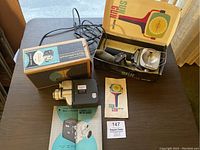 Overview of Bell & Howell projector with original box and Sun Gun light in box with manual.