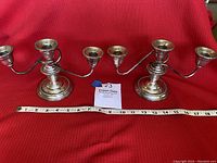 Set of two Kenilworth sterling silver candleholders placed on red fabric background with measuring tape showing length approx 10 inches