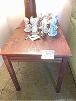 Front view of the wooden mid-century modern side table with ceramic figurines on top.