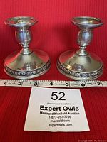 Pair of sterling silver candleholders showing size and ornate base detail.