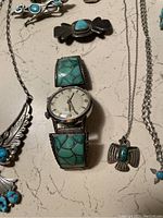 Center view showing Bulova watch with turquoise band alongside pendants and bracelets
