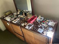 Wide view of dresser top covered with assorted necklaces, bracelets, earrings and brooches