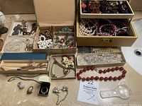 Overview of assorted jewelry trays, boxes and loose pieces on countertop