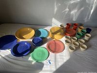 Overall set of vintage Fiestaware including plates, bowls, cups, and mugs in varied muted colors arranged on table