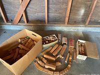 Overview photo showing multiple cardboard boxes filled with wooden train tracks and wooden block pieces.