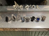 Front view of eight vintage silver rings with various stone settings lined up in a row