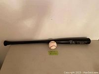 Photo of signed baseball and signed black wooden bat labeled 'Carlos Delgado'