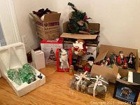 Wide view of all assorted Christmas decorations including tree, figurines, and ornaments in boxes and packaging.