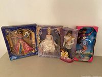 Four Disney-themed collectible dolls in their original packaging: Glamorous Jasmine, Cinderella, Flynn Rider, and In-line Skating Midge.