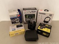 MapLock GPS anti-theft device in box with binoculars and other items