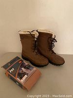 Full view of boots standing upright next to the Mudmax Pro ice grips box.