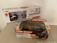 Photo of boxed Lite Hawk XL remote control helicopter and Land Shark off-road vehicle showing front packaging