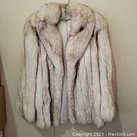Front view of short silver fox fur jacket on hanger