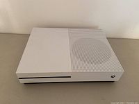 Front view of white and black Xbox One S console showing vent grid and Xbox logo