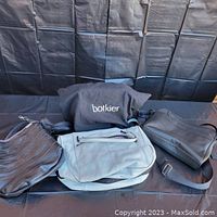 Lot of three Botkier purses arranged side by side with black backdrop.