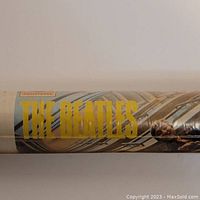 Close-up of poster packaging showing "THE BEATLES" text and part of album artwork, sealed in original shrink wrap