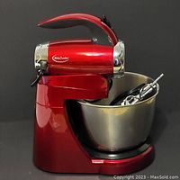 Side view of a red Betty Crocker stand mixer with a stainless steel bowl and two beaters inside the bowl.