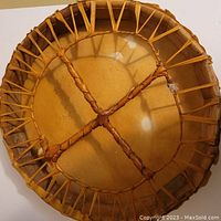 Back view showing cross-laced leather straps for grip and tension, wooden frame visible underneath.