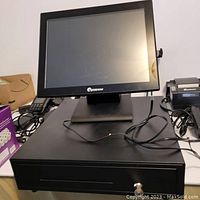 Front view of the Eposnow touchscreen display sitting on top of the black cash drawer with key lock.