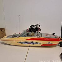 Side view of large remote control boat with yellow, red, and black 'X-Treme' graphics and measured length shown