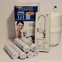 Overall lot items including reverse osmosis system box, six carbon block filters, chrome faucet box, and white water storage tank