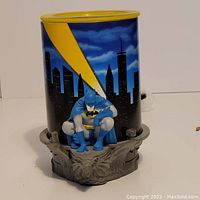 Front view of the Batman Scentsy warmer showing Batman figure crouching on skyline base and yellow bat signal on the shade