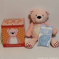 Benny Boo-Boo The Bear plush toy seated next to its matching branded box and the Clothesline scented sachet.