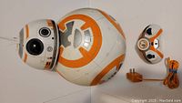 Top view of BB-8 robot body and head alongside its remote controller and power adapter.