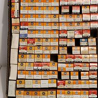 Photo showing a large number of vintage electron tubes in their original orange and white GE boxes along with a few RCA and Westinghouse boxes, neatly stacked.
