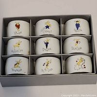 Set of nine white ceramic napkin rings with illustrated reindeer characters and names arranged in a box