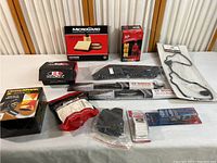 Car parts collection on white table including boxes and packaged items