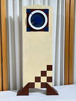 Front view of entire tower clock showing ivory body, brown geometric accents, and triangular feet