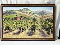 Full view of framed oil painting showing vineyard scene with hills and building.