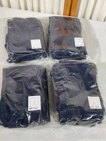 Four sealed packages of navy blue child’s play pants, displayed on a white surface.