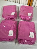 Four sealed packages each containing five pairs of fuchsia pink child's play pants in size 4 years, made of 100% organic cotton.