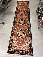 Full length view of the woven rug runner showing the overall pattern, color palette, and condition on a concrete floor.