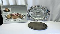 Boxed set including the tear-damaged box, silver-plated oval tray with fitted glass relish dish, and wooden carving board displayed against gray fabric background.