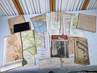 Overview photo showing the full collection of vintage aviation flight maps, flight log, typed flight instructions, emergency procedures, and the 1943 Practical Aviation magazine, laid out on a table.