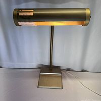 Full view of the vintage Chord-A-Lite table lamp on a white surface, showing a rounded rectangular base, flexible neck, and cylindrical light housing with illuminated chord guide.
