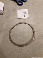 Silver necklace laid flat on a surface with a MaxSold lot card nearby.
