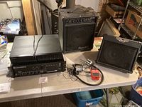 Full view of audio equipment on table including amplifiers, receiver, cables, and pedal